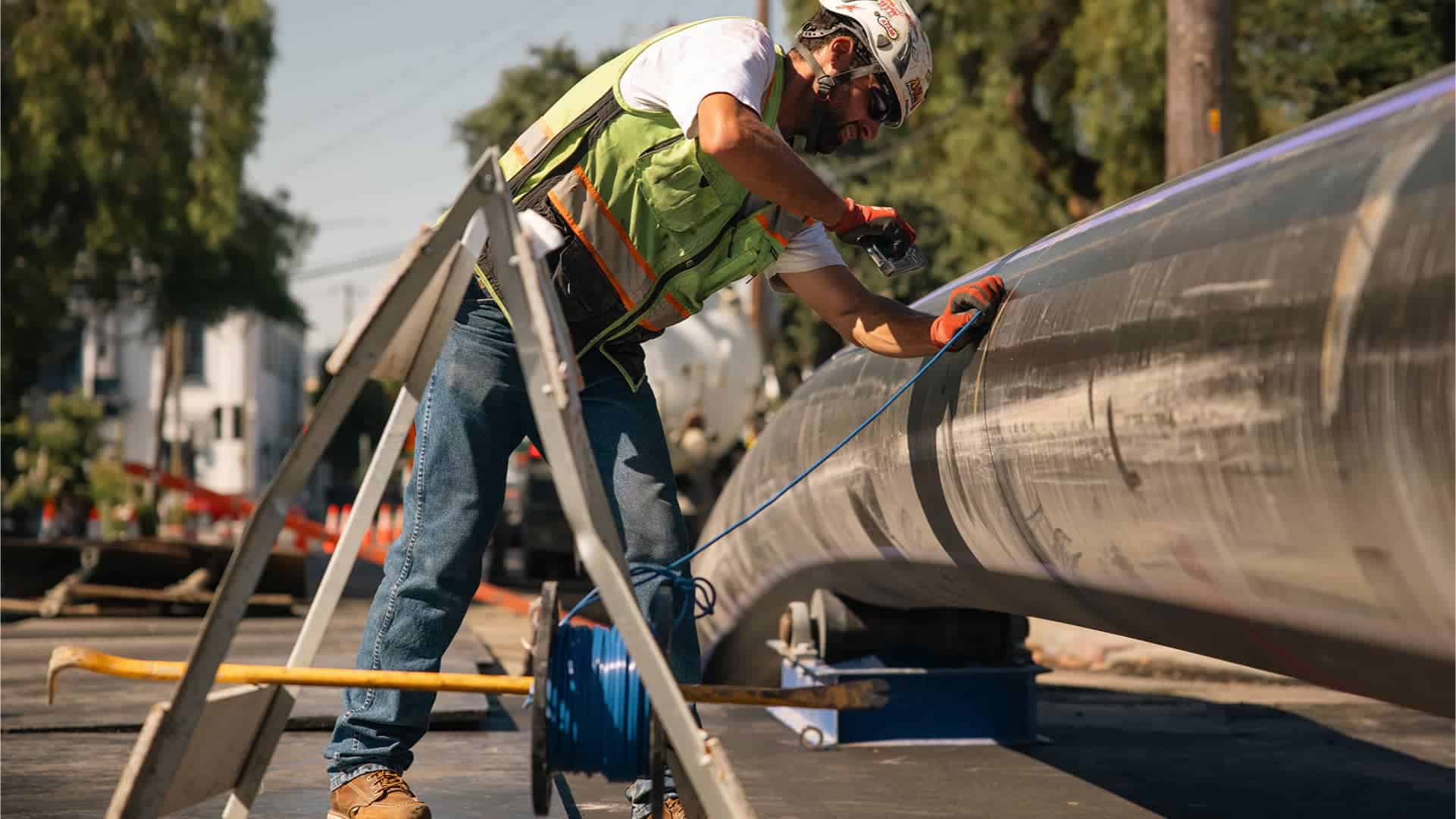A construction worker in a green vest and helmet at a construction site.