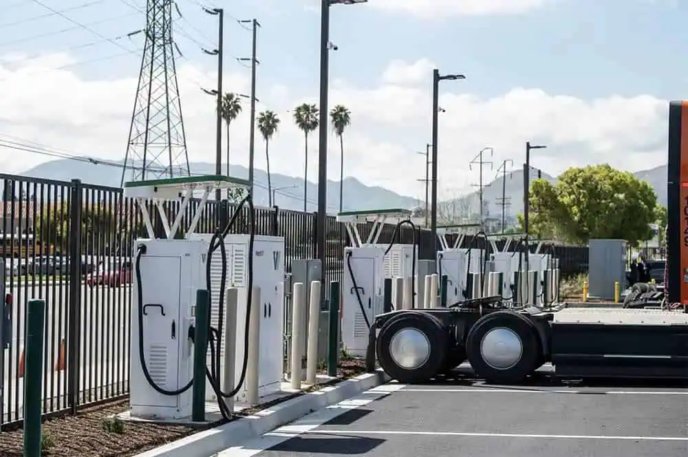 A truck parked beside an electric vehicle charging station, ready for recharging.